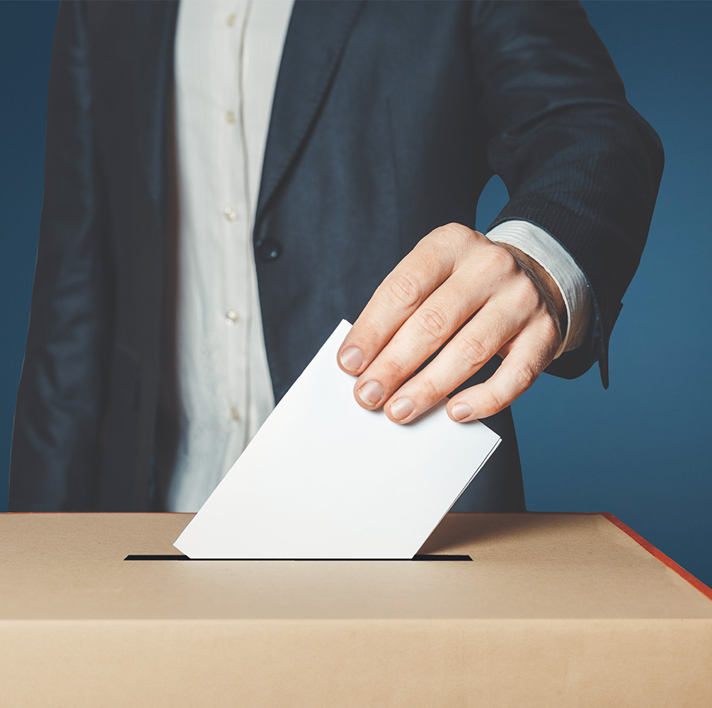 A man’s hand putting a ballot in a box